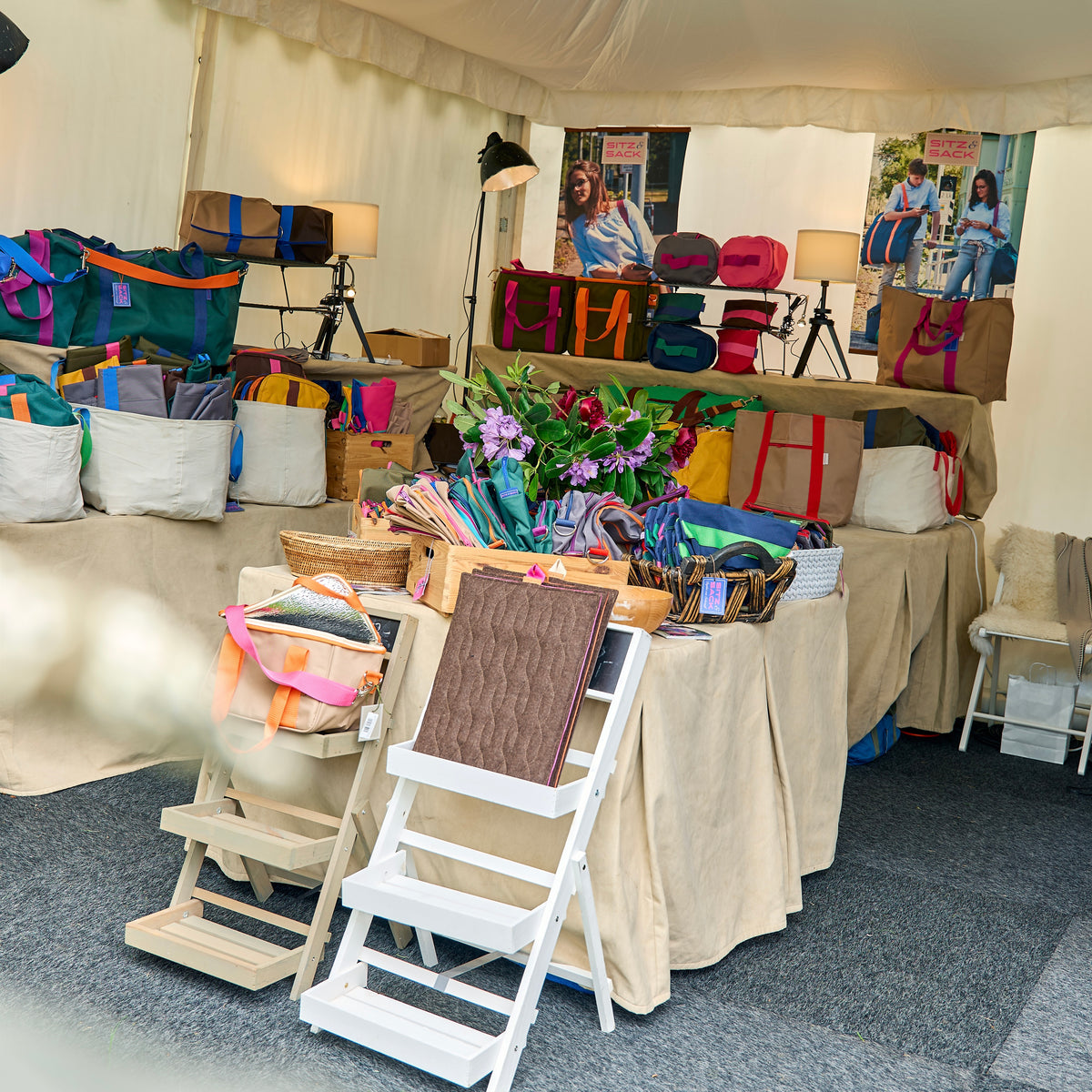 Stand von Sitz & Sack im Pagodenzelt auf einer Verkaufsausstellung, Tische voller Taschen und Kulturbeutel